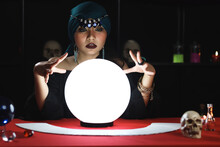 Mysterious Magnificent Beautiful Woman Fortune Teller In Black Dress Reading Future On Luminous Crystal Ball, Dark Witch Casting A Spell With Magical Ball