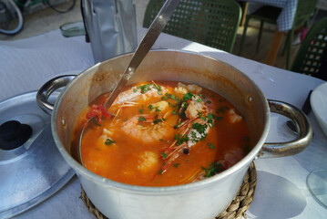 Wall Mural - Selective focus shot of a metallic bowl of seafood soup with greens, shrimps, and red sauce