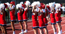 Cheerleaders Holding Their Pom Poms In The Air While Cheering To The Fans