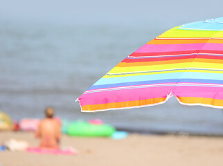 Wall Mural - parasol umbrella on the beach with swimmers having fun during the summer holidays