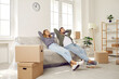 © Studio Romantic - Happy married couple taking break while moving in new home. Tired husband and wife resting and relaxing with hands behind heads on sofa in light room of their own modern house. Real estate concept