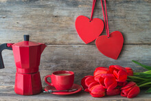 Valentine's Day Greeting Card; Red Geyser Coffee Maker, Cup Of Coffee, Bunch Of Red Tulips And Two Red Hearts Decorations On Old Wooden Background