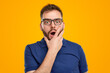 Shocked man with hands on yellow background