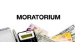 MORATORIUM words and 3d illustration currencies, notepad, fountain pen and calculator background