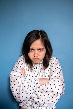 Studio Portrait Of Angry Woman Against Blue Background