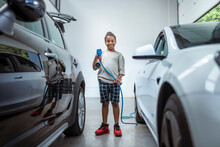 UK, Portrait Of Smiling Boy Holding Electric Plug At Electric Car
