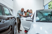 UK, Parents With Daughter And Son Looking At New Car In Showroom