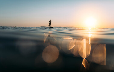 Silhouette of a man paddleboarding, copy space