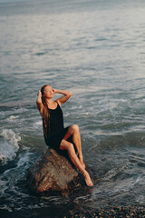 Poster - Scenic view of a model with a black dress posing for the picture on the beach