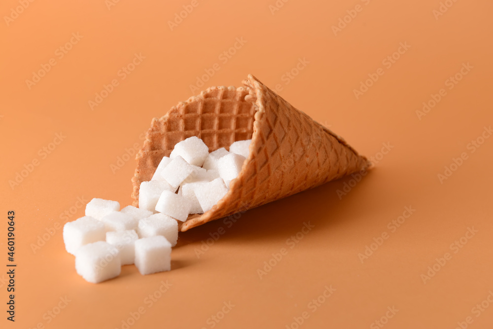 Waffle cone with sweet sugar on color background