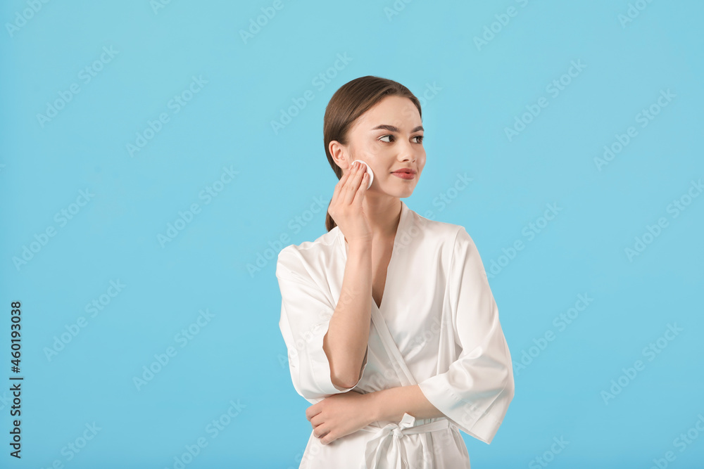 Beautiful young woman with cotton pad on color background