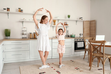 Poster - Young woman and her little daughter dancing in kitchen