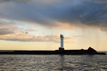 Wall Mural - Lighthouse with a solar battery. Baltic sea. Dramatic sunset sky after the storm. Glowing clouds, golden sunlight. Symbol of hope and peace. Architecture, travel destinations, navigation, sailing