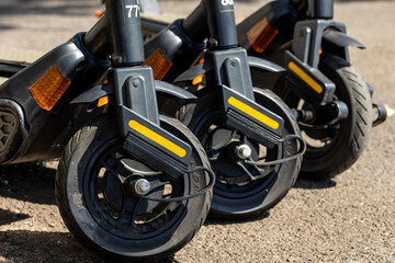 Sticker - Close-up shot of motor scooters in a row parked outdoors on a concrete ground