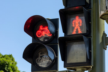 Poster - Red traffic lights of bicycles and pedestrians against a blue sky on a pole on the street