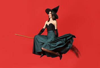 Young witch with broom on color background