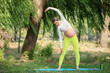 © Pixel-Shot - Young pregnant woman practicing yoga in park