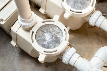 Running pool pump system, inside. Perspective view of two installed pool pumps with connected pipes. Used to filter and circulate water for a standard pool or inground pool. Selective focus.