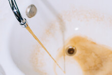 Rusty Water Flows From The Tap Into The Bathtub