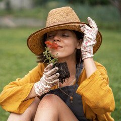 Wall Mural - Woman is holding a petunia flower in a peat pot.