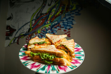Wall Mural - Classic club sandwich on a colored plate. The sandwich filling includes ham, cheese, lettuce, tomato slices. Light background. Close-up.