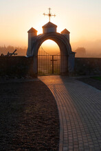 Church Architecture. A Stone Gate With An Arch And A Catholic Cross Above It. Morning. Fog