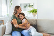 © Graphicroyalty - Close up of sweet pretty daughter cuddling with her young mother. Lovely mother embracing her cute daughter on the sofa at home.