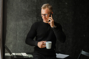 office worker with glasses talking on the phone with a cup of coffee 