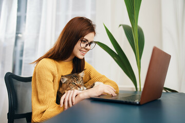 woman in yellow sweater at home in front of laptop next to cat interior lifestyle