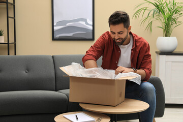 Canvas Print - Man unpacking parcel at home. Online shopping