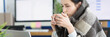 © H_Ko - Sick young woman sits in warm blanket with cup at workplace