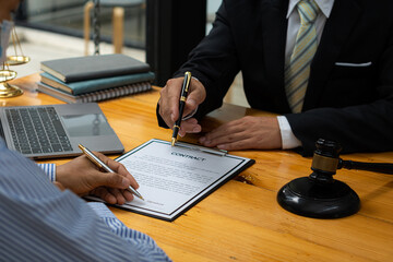 Male businessman and lawyer discussing legal matters and lawyers discuss contract documents sitting at a table. Legal concepts, advice, legal services. with a judge's hammer and golden scales on the d