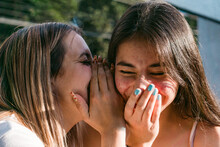 Smiling Teenager Telling Secret To Girlfriend On Street