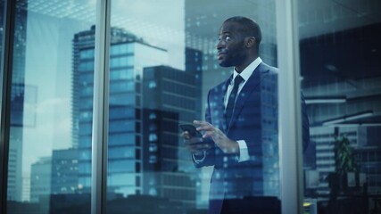 Poster - Portrait of Successful Black Businessman Wearing Suit Standing, Using Smartphone Looking out of the Window. Successful African CEO Planning e-Commerce Investment Strategy. From Outside Shot