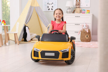 Poster - Adorable child driving toy car in room at home