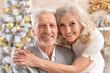 © aletia2011 - Portrait of hugging senior couple with blurred Christmas decorations