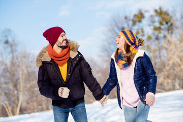 Wall Mural - Photo of cheerful young couple happy positive smile walk outside hold hands together winter snow vacation laugh