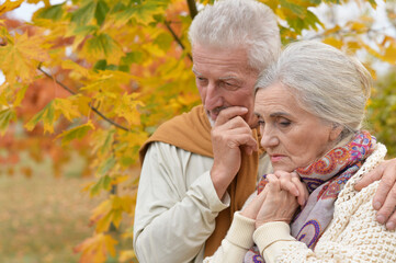 Portrait of sad senior couple in autumn park