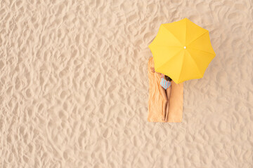 Wall Mural - Woman resting under yellow beach umbrella at sandy coast, aerial view. Space for text