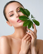 © Valua Vitaly - Beautiful woman with green leave near face and body.  Closeup girl's face with green leave. Skin care beauty treatments concept.