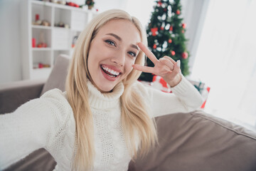 Canvas Print - Photo of happy cheerful young woman sit couch make v-sign selfie xmas mood indoors inside house home