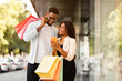 © Prostock-studio - Portrait of happy black couple using phone with shopping bags