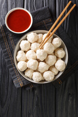 Wall Mural - Bakso ayam Recipe Indonesian Meatballs from chicken with sauce close up in the bowl on the table. Vertical top view from above