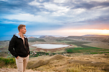 Wall Mural - A young man conquered the top of the mountain at dawn. Beautiful mountain landscape with a slope. The concept of enjoying nature.