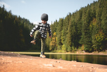 Small Kid In A Plaid Shirt And Gray Hat On The Forest Lake Coast. Childhood With Nature Loving Concept