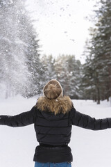 Wall Mural - Woman throwing snow into the air during cold winter day