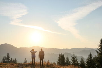 Wall Mural - Couple enjoying sunrise in mountains, back view. Space for text