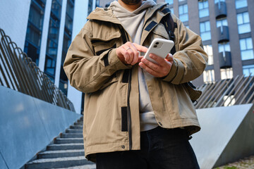 Wall Mural - a man with a smartphone in his hands stands near the business center. a businessman is sending a tex