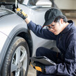 © zephyr_p - Asian auto mechanic holding digital tablet checking car wheel and tire in auto service garage. Mechanical maintenance engineer working in automotive industry. Automobile servicing and repair concept