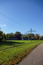 Autumnal Landscape Background With Clear Blue Sky. City Buses In The Parking. Electric Poles For Trams. Green Grass Covered With Dry Golden Leaves. Kopli, Tallinn, Estonia, Europe. September 2021